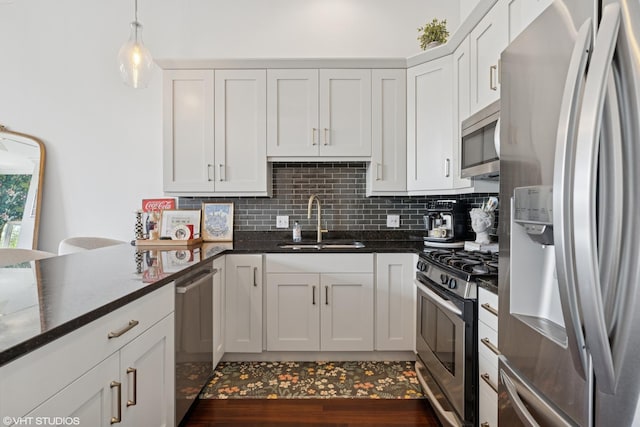 2549 N Southport Ave Unit 3, Chicago, IL 60614 - kitchen featuring appliances with stainless steel finishes, tasteful backsplash, hanging light fixtures, white cabinetry, and dark stone countertops