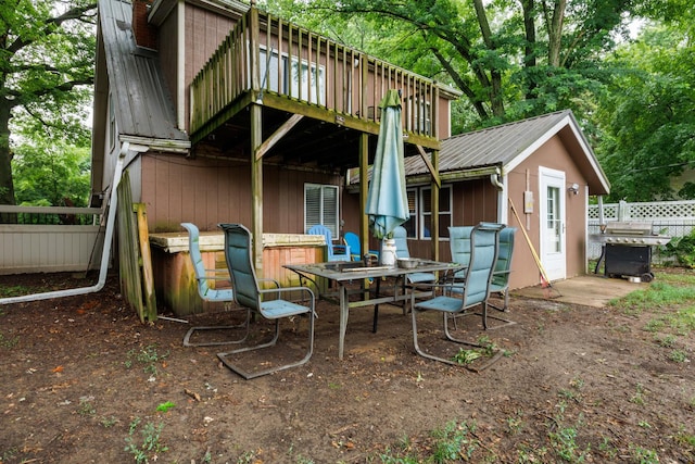 17366 Walden Rd, Hudson, IL 61748 - rear view of property with a metal roof, a wooden deck, and outdoor dining area