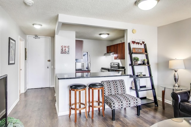 30 E Huron St Unit 2603, Chicago, IL 60611 - kitchen with dark countertops, dark wood finished floors, a kitchen breakfast bar, a textured ceiling, and stainless steel range with electric stovetop