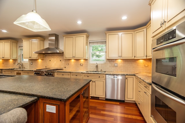 2900 W Birchwood Ave, Chicago, IL 60645 - kitchen featuring stainless steel appliances, cream cabinets, wall chimney range hood, dark wood finished floors, and recessed lighting