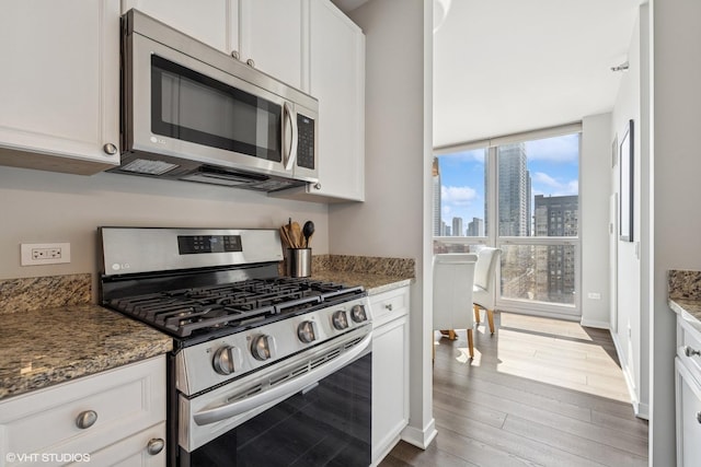 200 W Grand Ave Unit 1803, Chicago, IL 60654 - kitchen with stainless steel appliances, wood finished floors, a skyline view, and white cabinets