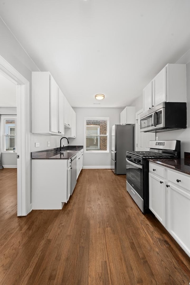 4604 N Monticello Ave Unit 3E, Chicago, IL 60625 - kitchen featuring appliances with stainless steel finishes, dark countertops, dark wood finished floors, and plenty of natural light