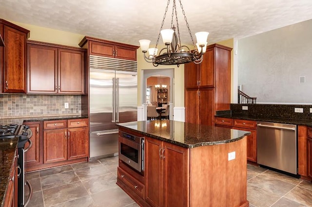 12499 Ayrshire Ln, Loves Park, IL 61111 - kitchen featuring stainless steel appliances, arched walkways, a chandelier, a center island, and dark stone countertops