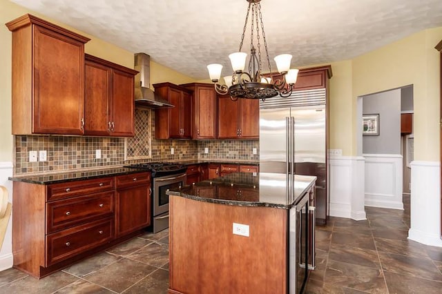 12499 Ayrshire Ln, Loves Park, IL 61111 - kitchen with appliances with stainless steel finishes, wall chimney exhaust hood, a chandelier, a kitchen island, and backsplash