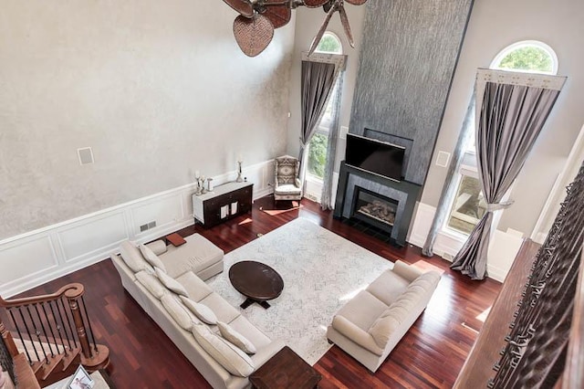 12499 Ayrshire Ln, Loves Park, IL 61111 - living room featuring a towering ceiling, a tile fireplace, wainscoting, a ceiling fan, and a decorative wall
