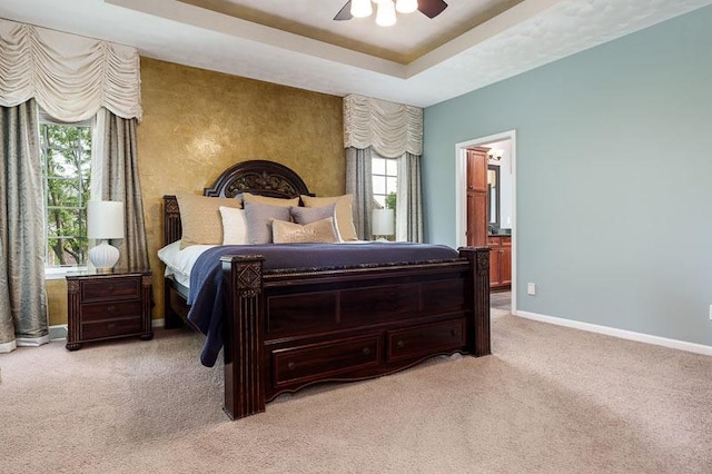 12499 Ayrshire Ln, Loves Park, IL 61111 - bedroom featuring light colored carpet, a tray ceiling, connected bathroom, and ceiling fan
