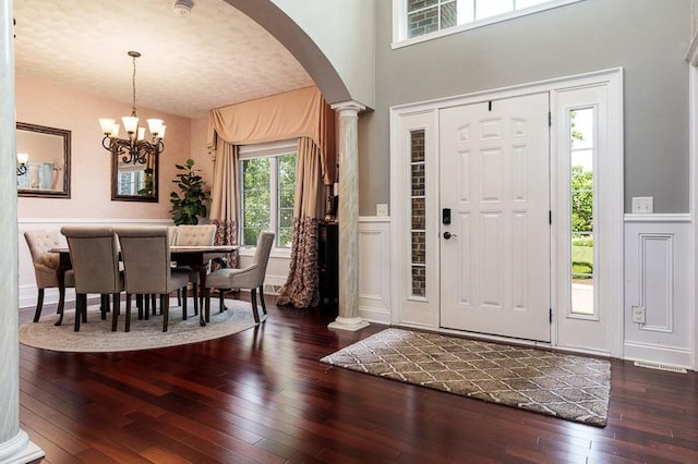 12499 Ayrshire Ln, Loves Park, IL 61111 - foyer entrance featuring arched walkways, ornate columns, hardwood / wood-style floors, a chandelier, and a wainscoted wall