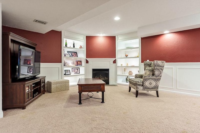 12499 Ayrshire Ln, Loves Park, IL 61111 - sitting room with a decorative wall, built in features, wainscoting, a fireplace with flush hearth, and carpet flooring