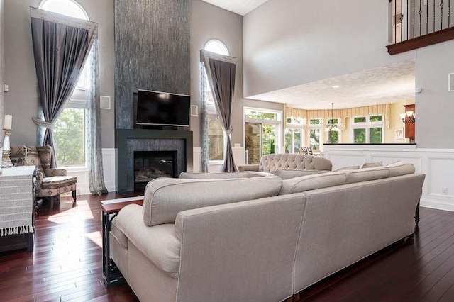 12499 Ayrshire Ln, Loves Park, IL 61111 - living room with a towering ceiling, dark wood finished floors, a fireplace, a decorative wall, and a wainscoted wall