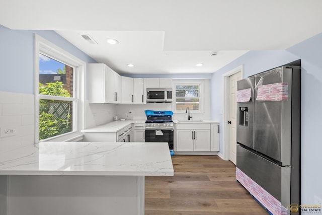 9509 S Merrion Ave, Chicago, IL 60617 - kitchen with stainless steel appliances, light stone countertops, a peninsula, white cabinets, and tasteful backsplash