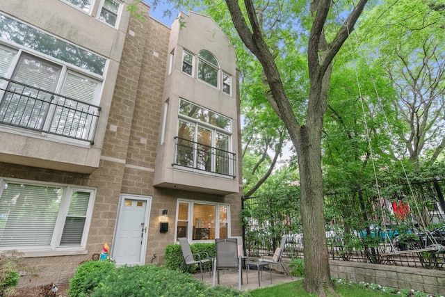 1212 W School St, Chicago, IL 60657 - rear view of house with a patio area, a balcony, and stone siding