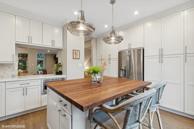 1212 W School St, Chicago, IL 60657 - kitchen with stainless steel appliances, wooden counters, wood finished floors, recessed lighting, and white cabinets
