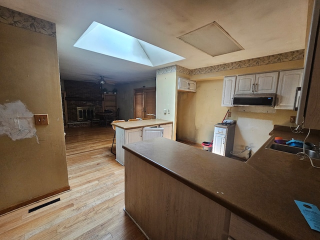 340 Somerset Dr, Streamwood, IL 60107 - kitchen with a peninsula, light wood-style flooring, a fireplace, exhaust hood, and a skylight