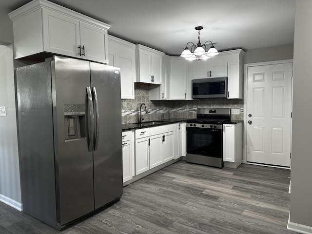 207 W 2nd St, Streator, IL 61364 - kitchen featuring appliances with stainless steel finishes, dark countertops, dark wood-style floors, a chandelier, and white cabinets