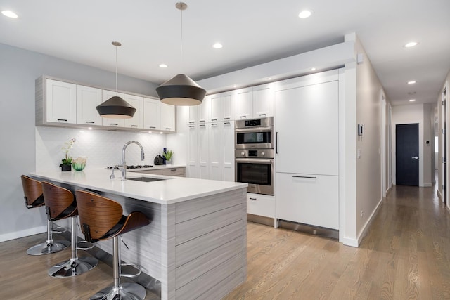 927 N Damen Ave Unit 2, Chicago, IL 60622 - kitchen with stainless steel double oven, a peninsula, light wood-style floors, backsplash, and recessed lighting