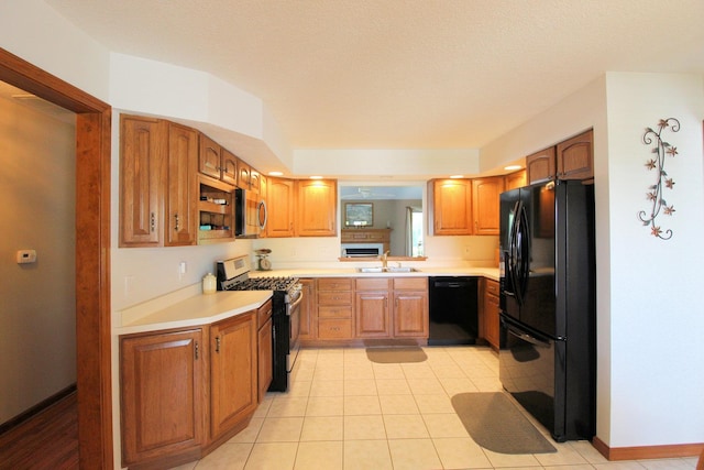 396 W 8th St, Manteno, IL 60950 - kitchen with black appliances, light countertops, brown cabinets, and light tile patterned flooring