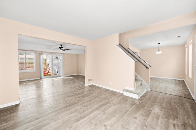 995 Serendipity Dr, Aurora, IL 60504 - unfurnished living room with light wood finished floors, stairs, ceiling fan, and a chandelier