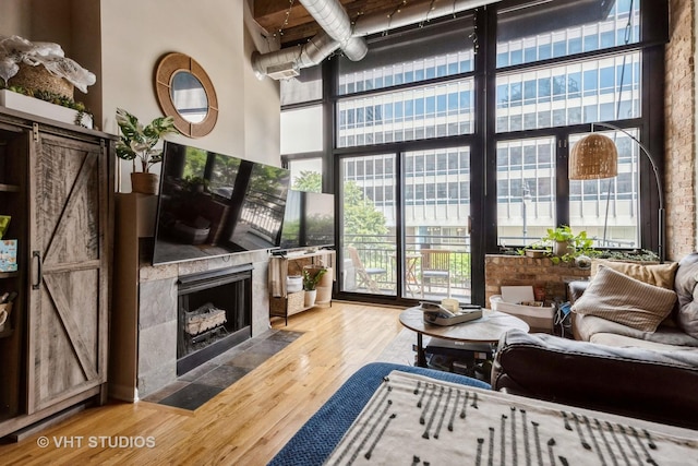 525 W Superior St Unit 224, Chicago, IL 60654 - living room featuring a high ceiling, healthy amount of natural light, a tile fireplace, a barn door, and wood finished floors