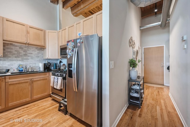525 W Superior St Unit 224, Chicago, IL 60654 - kitchen featuring stainless steel appliances, light wood finished floors, tasteful backsplash, dark countertops, and beamed ceiling