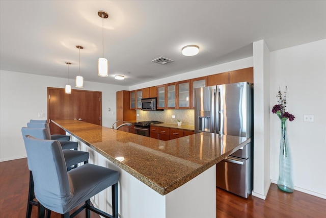 301 N Neil St Unit 609, Champaign, IL 61820 - kitchen with appliances with stainless steel finishes, brown cabinets, dark wood finished floors, a kitchen breakfast bar, and glass insert cabinets