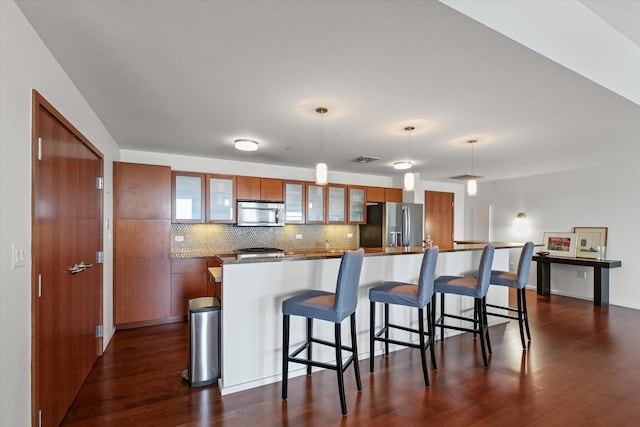 301 N Neil St Unit 609, Champaign, IL 61820 - kitchen featuring stainless steel appliances, dark wood-style floors, decorative backsplash, brown cabinets, and a kitchen bar
