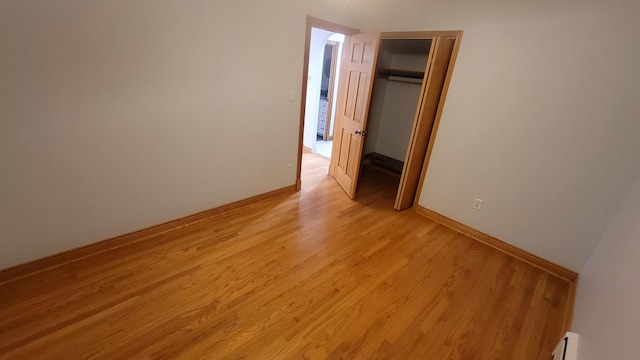 5448 W Agatite Ave, Chicago, IL 60630 - unfurnished bedroom featuring a baseboard radiator, light wood-style flooring, and a closet