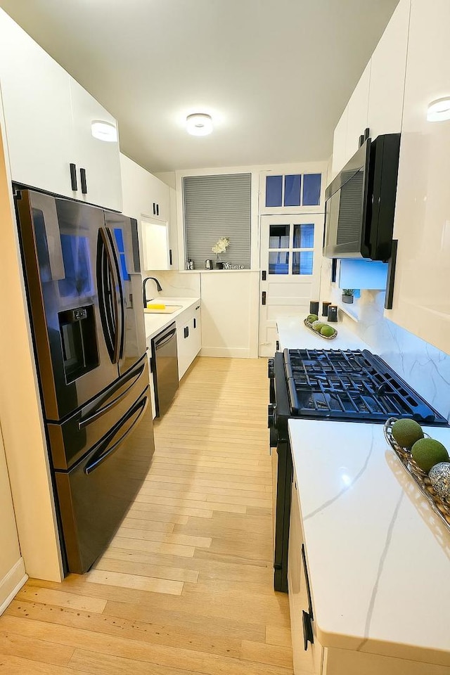 230 N Oak Park Ave Unit 1K, Oak Park, IL 60302 - kitchen with black appliances, light wood finished floors, light countertops, white cabinetry, and tasteful backsplash
