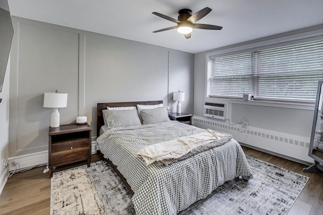 1333 W Touhy Ave Unit 102, Park Ridge, IL 60068 - bedroom with wood finished floors, a baseboard heating unit, cooling unit, ceiling fan, and radiator heating unit