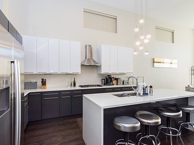 2036 W Huron St, Chicago, IL 60612 - kitchen featuring stainless steel appliances, wall chimney exhaust hood, dark wood-type flooring, a breakfast bar, and modern cabinets