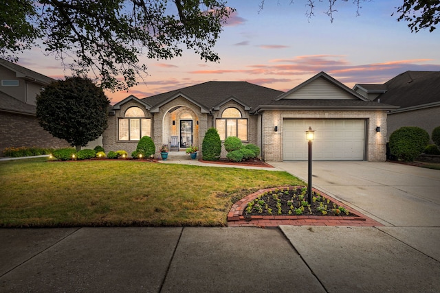 18049 Brittany Ln, Lansing, IL 60438 - view of front of home featuring driveway, a lawn, an attached garage, and brick siding