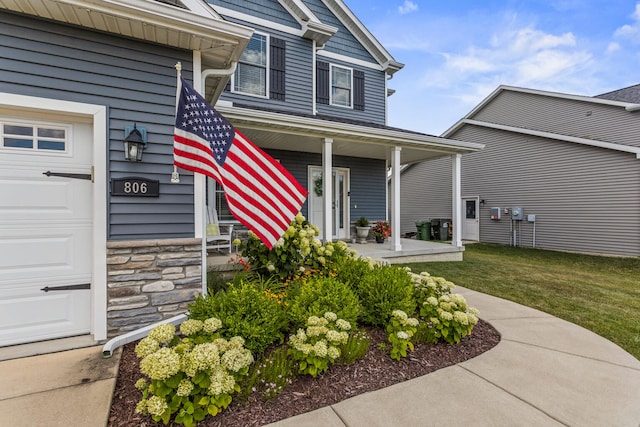 806 Cole Ln, Mahomet, IL 61853 - property entrance featuring covered porch, stone siding, a garage, and a lawn