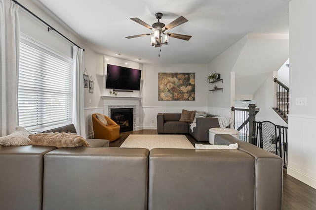 806 Cole Ln, Mahomet, IL 61853 - living room with a ceiling fan, dark wood-type flooring, a wainscoted wall, a glass covered fireplace, and stairs