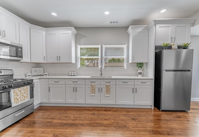 4438 S Knox Ave, Chicago, IL 60632 - kitchen with stainless steel appliances, decorative backsplash, white cabinets, light countertops, and wood finished floors