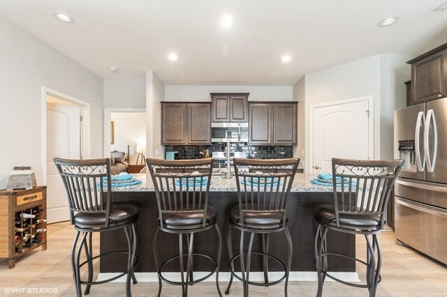 1029 Carolina Ct, Pingree Grove, IL 60140 - kitchen with stainless steel appliances, light wood-style floors, dark brown cabinetry, light stone counters, and recessed lighting
