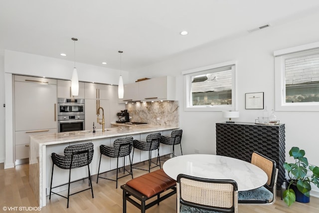 1547 N Wood St Unit 2, Chicago, IL 60622 - kitchen with stainless steel appliances, a peninsula, decorative backsplash, a breakfast bar area, and modern cabinets