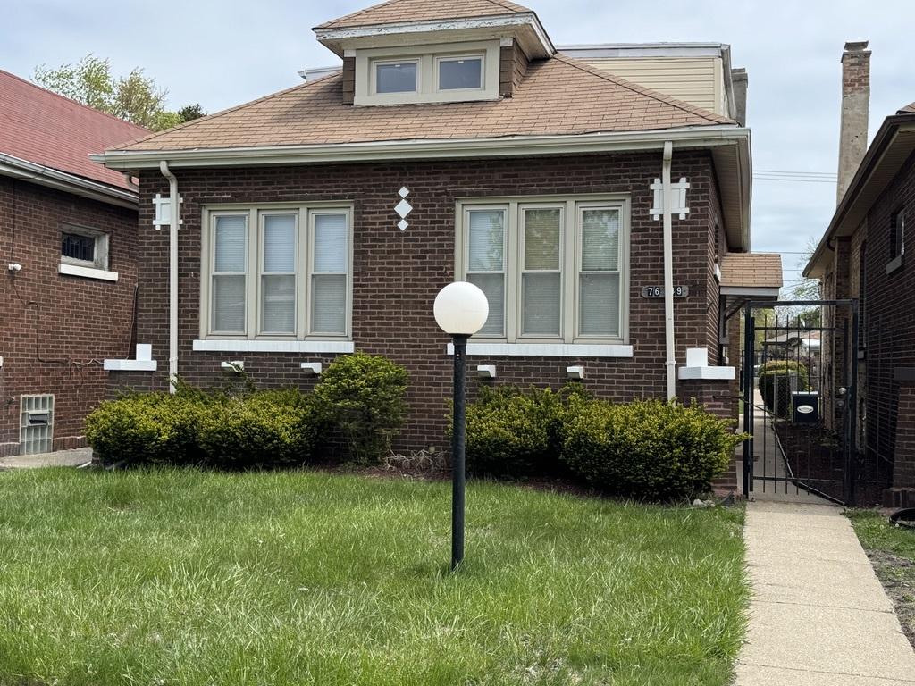7649 S Michigan Ave, Chicago, IL 60619 - bungalow featuring brick siding, a front yard, and a gate