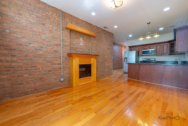 4137 S Prairie Ave Unit 3, Chicago, IL 60653 - kitchen with appliances with stainless steel finishes, brick wall, light wood finished floors, dark countertops, and a fireplace