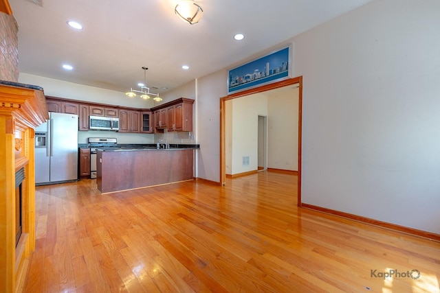 4137 S Prairie Ave Unit 3, Chicago, IL 60653 - kitchen with appliances with stainless steel finishes, dark countertops, a peninsula, a chandelier, and light wood-style floors