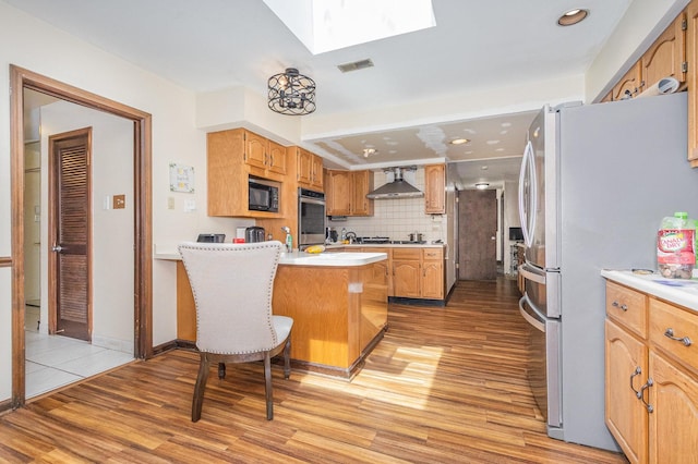 1717 Oak Lane Rd, Flossmoor, IL 60422 - kitchen with stainless steel appliances, a skylight, light wood finished floors, a peninsula, and wall chimney exhaust hood