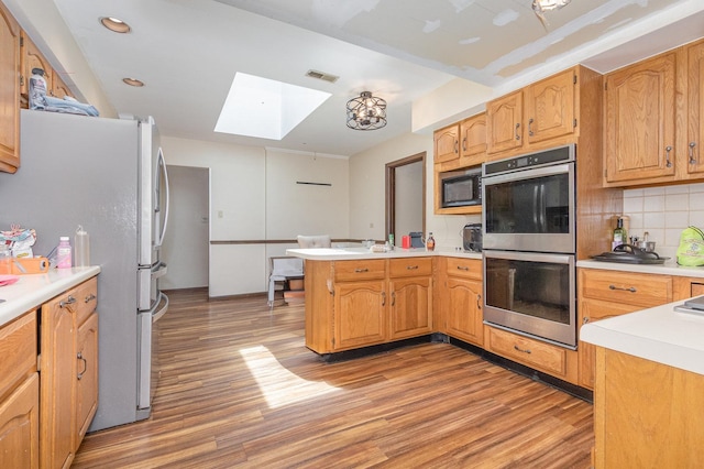 1717 Oak Lane Rd, Flossmoor, IL 60422 - kitchen with stainless steel double oven, a skylight, a peninsula, freestanding refrigerator, and black microwave