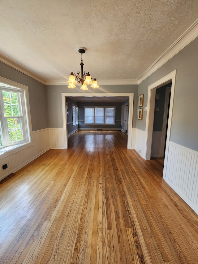 661 S Swain Ave, Elmhurst, IL 60126 - spare room featuring a chandelier, a textured ceiling, hardwood / wood-style floors, wainscoting, and ornamental molding
