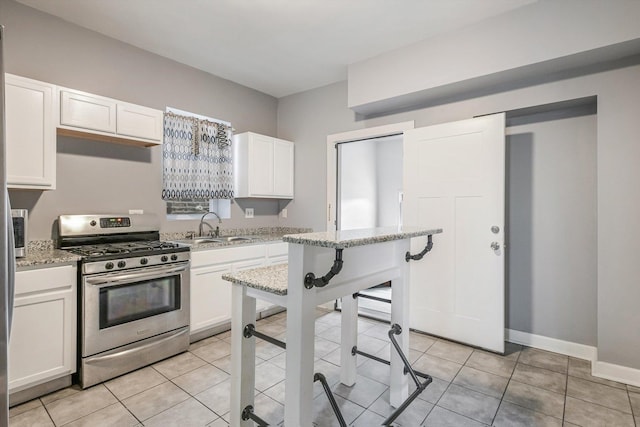 2630 S Spaulding Ave, Chicago, IL 60623 - kitchen with gas stove, white cabinetry, light stone counters, and light tile patterned floors