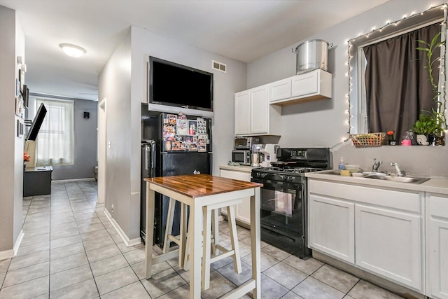 2630 S Spaulding Ave, Chicago, IL 60623 - kitchen with black gas range oven, light tile patterned flooring, refrigerator, and white cabinetry