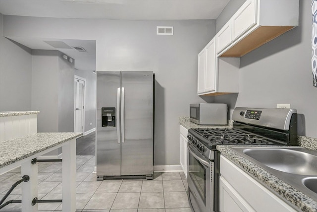 2630 S Spaulding Ave, Chicago, IL 60623 - kitchen with stainless steel appliances, light tile patterned flooring, white cabinets, and light stone countertops