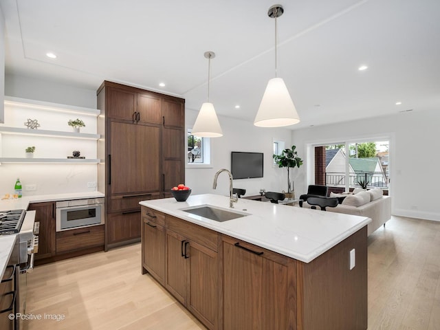 2841 N Southport Ave Unit 2, Chicago, IL 60657 - kitchen featuring open shelves, light wood-type flooring, open floor plan, a kitchen island with sink, and decorative light fixtures