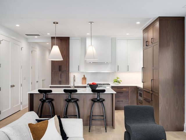 2841 N Southport Ave Unit 2, Chicago, IL 60657 - kitchen with an island with sink, light countertops, a breakfast bar area, recessed lighting, and decorative light fixtures