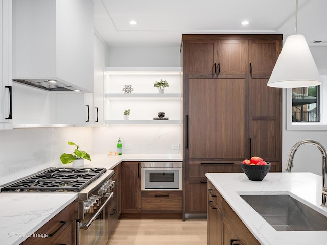 2841 N Southport Ave Unit 2, Chicago, IL 60657 - kitchen featuring appliances with stainless steel finishes, extractor fan, open shelves, light wood finished floors, and light stone counters