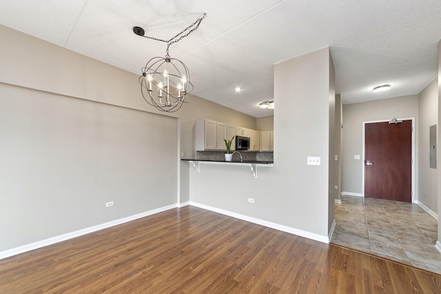 6420 Double Eagle Dr Unit 510, Woodridge, IL 60517 - kitchen featuring stainless steel microwave, a chandelier, dark countertops, wood finished floors, and a breakfast bar area