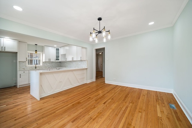 8623 S Prairie Ave, Chicago, IL 60619 - kitchen featuring light countertops, white cabinetry, light wood-style flooring, backsplash, and crown molding
