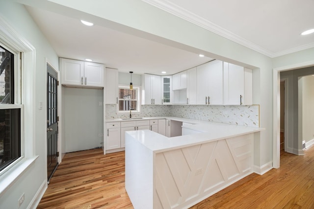 8623 S Prairie Ave, Chicago, IL 60619 - kitchen featuring a peninsula, light wood-type flooring, tasteful backsplash, white cabinetry, and ornamental molding